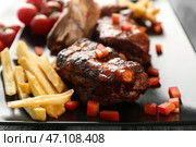 Вкусные жареные ребрышки с картофелем фри на тарелке, крупным планом. Стоковое фото, фотограф Pixel_shot / Фотобанк Лори