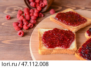 Вкусный поджаренный хлеб и малиновое варенье на деревянной доске. Стоковое фото, фотограф Pixel_shot / Фотобанк Лори