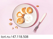 Тарелка с вкусными сырниками и сметаной на розовом фоне. Стоковое фото, фотограф Pixel_shot / Фотобанк Лори