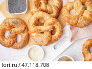 Доска с вкусными кренделями, маком и кунжутом на светлом фоне, крупным планом. Стоковое фото, фотограф Pixel_shot / Фотобанк Лори