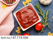 Композиция с миской вкусной томатной пасты, сырой пастой фарфалле и розмарином на сером фоне. Стоковое фото, фотограф Pixel_shot / Фотобанк Лори