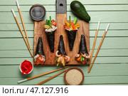 Доска с вкусными суши-конусами, соевым соусом, кунжутом, имбирем и авокадо на цветном деревянном фоне. Стоковое фото, фотограф Pixel_shot / Фотобанк Лори