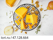 Охладительная решетка с кусочками вкусного чеддер-сыра на светлом фоне. Стоковое фото, фотограф Pixel_shot / Фотобанк Лори