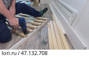 A man assembles the base of a couch. He fastens wooden slats with screws. Using a screwdriver. Стоковое видео, видеограф Vadzim Yakubovich / Фотобанк Лори
