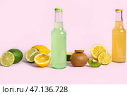 Бутылки свежего газированного напитка и фрукты на фиолетовом фоне. Стоковое фото, фотограф Pixel_shot / Фотобанк Лори