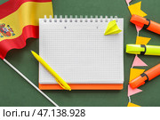 Блокнот с канцелярскими принадлежностями и флагом Испании на зеленом фоне. Стоковое фото, фотограф Pixel_shot / Фотобанк Лори