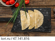 Доска с сырыми чебуреками, зеленым луком и помидорами на деревянном фоне. Стоковое фото, фотограф Pixel_shot / Фотобанк Лори