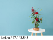 Чаша с красивой икебаной на столе возле синей стены. Стоковое фото, фотограф Pixel_shot / Фотобанк Лори