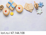 Деревянный дрейдель, подарочная коробка и еда для празднования Хануки на светлом фоне. Стоковое фото, фотограф Pixel_shot / Фотобанк Лори