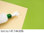 Бутылка клея с листом бумаги на зеленом фоне, крупным планом. Стоковое фото, фотограф Pixel_shot / Фотобанк Лори