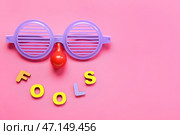 Композиция с очками, клоунским носом и словом FOOLS на цветном фоне. Стоковое фото, фотограф Pixel_shot / Фотобанк Лори
