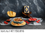 Вкусный азиатский плов с овощным салатом, лепешкой и Кораном на темном фоне. Стоковое фото, фотограф Pixel_shot / Фотобанк Лори