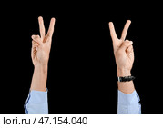 Бизнесмен показывает победный жест на черном фоне. Стоковое фото, фотограф Pixel_shot / Фотобанк Лори