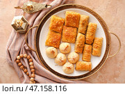 Поднос со вкусными восточными сладостями, арабскими светильниками и тасбихом на гранж-фоне. Стоковое фото, фотограф Pixel_shot / Фотобанк Лори