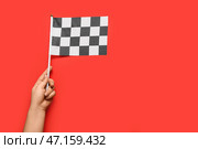 Женская рука с гоночным флагом на цветном фоне. Стоковое фото, фотограф Pixel_shot / Фотобанк Лори