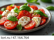 A classic Italian Caprese salad made with fresh red cherry tomatoes, tender mozzarella and bright basil leaves. The dish is seasoned with ground black pepper, sea salt and a drizzle of olive oil, which gives it a delicious shine. The food is served on a ceramic plate, and the basil leaves are slightly blurred in the background, creating a natural and fresh atmosphere. The combination of colors - red, white and green - makes this dish not only delicious, but also aesthetically pleasing. Стоковое AI-изображение, AI-художник Анна Кривицкая / Фотобанк Лори