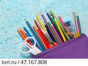 Чемодан с карандашами, ножницами, ластиком и точилкой на цветном фоне, крупным планом. Стоковое фото, фотограф Pixel_shot / Фотобанк Лори