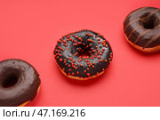 Вкусные глазированные пончики на красном фоне крупным планом. Стоковое фото, фотограф Pixel_shot / Фотобанк Лори