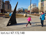 RAMENSKOYE, Russia - March 16, 2025 - Sundial. A little girl is having fun around the sundial on a city street. Редакционное фото, фотограф Кутина Татьяна / Фотобанк Лори