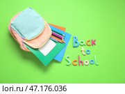 ВЕРНИТЕСЬ В ШКОЛУ, рюкзак и канцелярские товары на зеленом фоне. Стоковое фото, фотограф Pixel_shot / Фотобанк Лори