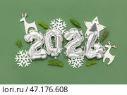 Композиция с фигурой 2024 из серебряных фольгированных шаров, новогодними украшениями и веточками ели на зеленом фоне. Стоковое фото, фотограф Pixel_shot / Фотобанк Лори