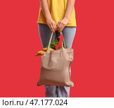 Молодая женщина с мешком еды и стрелкой на красном фоне. Концепция роста цен. Стоковое фото, фотограф Pixel_shot / Фотобанк Лори