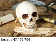 Человеческий череп с древними манускриптами, мечом и подзорной трубой на коричневом деревянном фоне. Стоковое фото, фотограф Pixel_shot / Фотобанк Лори