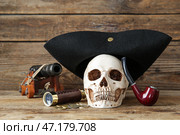 Человеческий череп в пиратской шляпе, трубке и трубке на коричневом деревянном фоне. Стоковое фото, фотограф Pixel_shot / Фотобанк Лори