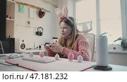 Smiling girl in bunny ears and futuristic glasses enjoys gaming, gripping controller with excitement. Immersed in virtual adventure, celebrates success in digital world, radiating joy and enthusiasm. Стоковое видео, видеограф Енваев Андрей / Фотобанк Лори