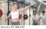 Slender girl, together with other athletes, does a warm-up using a long stick in the gym. Стоковое видео, видеограф Яков Филимонов / Фотобанк Лори