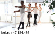 Group of enthusiastic adult women and men ballet students, led by female choreographer, focused on mastering graceful Demi rond de jambe par terre move at barre in mirrored sunlit airy dance studio. Стоковое видео, видеограф Яков Филимонов / Фотобанк Лори