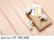Подарочная коробка, цветы ромашки и открытка с текстом ДОБРО ПОЖАЛОВАТЬ ВЕСНА на цветном деревянном фоне. Стоковое фото, фотограф Pixel_shot / Фотобанк Лори