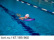Child Practicing Swimming Skills With Flotation Device in Indoor Pool Environment. Стоковое фото, фотограф Aleksandr Golubev / Фотобанк Лори