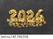 Композиция с фигурой 2024 из золотых фольгированных шаров и конфетти на темном фоне. Стоковое фото, фотограф Pixel_shot / Фотобанк Лори