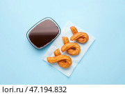 Пергамент с вкусными чуррос и соусом из расплавленного шоколада на цветном фоне. Стоковое фото, фотограф Pixel_shot / Фотобанк Лори