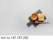 Стеклянная банка со сладким медом, гребенкой и ковшом на сером фоне. Стоковое фото, фотограф Pixel_shot / Фотобанк Лори