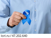 Человек с голубой лентой, крупным планом. Концепция рака толстой кишки. Стоковое фото, фотограф Pixel_shot / Фотобанк Лори
