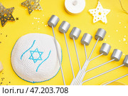 Менора с еврейской шляпой для празднования Хануки на желтом фоне крупным планом. Стоковое фото, фотограф Pixel_shot / Фотобанк Лори