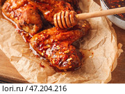 Вкусные жареные куриные крылышки с горячим медом на столе, крупным планом. Стоковое фото, фотограф Pixel_shot / Фотобанк Лори