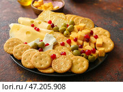 Тарелка с вкусными крекерами с сыром и закусками на фоне гранж. Стоковое фото, фотограф Pixel_shot / Фотобанк Лори
