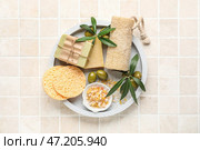Доска с кусками мыла, оливками, губками, морской солью и мочалкой на фоне бежевой плитки. Стоковое фото, фотограф Pixel_shot / Фотобанк Лори