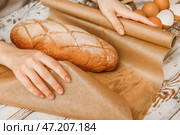 Женщина заворачивает свежий хлеб в бумагу для выпечки на белом деревянном фоне, крупным планом. Стоковое фото, фотограф Pixel_shot / Фотобанк Лори