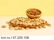 Доска и миска с вкусными фисташками на желтом фоне. Стоковое фото, фотограф Pixel_shot / Фотобанк Лори