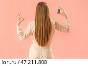 Молодая женщина с ингалятором показывает ОК на розовом фоне, вид сзади. Стоковое фото, фотограф Pixel_shot / Фотобанк Лори