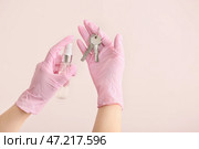 Женщина дезинфицирует ключи от дома на цветном фоне. Стоковое фото, фотограф Pixel_shot / Фотобанк Лори