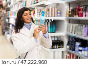Adult Latina choosing haircare cosmetics in specialized boutique. Стоковое фото, фотограф Яков Филимонов / Фотобанк Лори