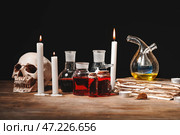 Зелья, человеческий череп, старая книга и свечи на столе алхимика. Стоковое фото, фотограф Pixel_shot / Фотобанк Лори
