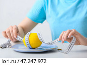 Женщина с тарелкой, лимоном и измерительной лентой за столом. Понятие анорексии. Стоковое фото, фотограф Pixel_shot / Фотобанк Лори