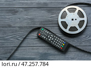 Современный пульт дистанционного управления телевизором и кинолента на темном деревянном фоне. Стоковое фото, фотограф Pixel_shot / Фотобанк Лори
