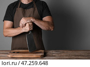 Повар-мужчина с тесаком для мяса и разделочной доской возле стола на сером фоне. Стоковое фото, фотограф Pixel_shot / Фотобанк Лори